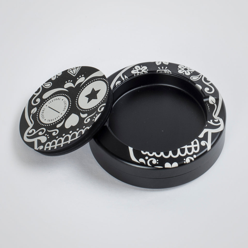 Icetool The Can, black aluminum snus can for portion snus and nicotine pouches. Extra storage under the lid for used portions. Black aluminum with Sugar Skull graphics. Photo of an open can.